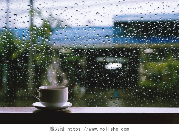 下雨天桌子上的一杯咖啡冒着热气热饮料在下雨天的木桌上的杯子